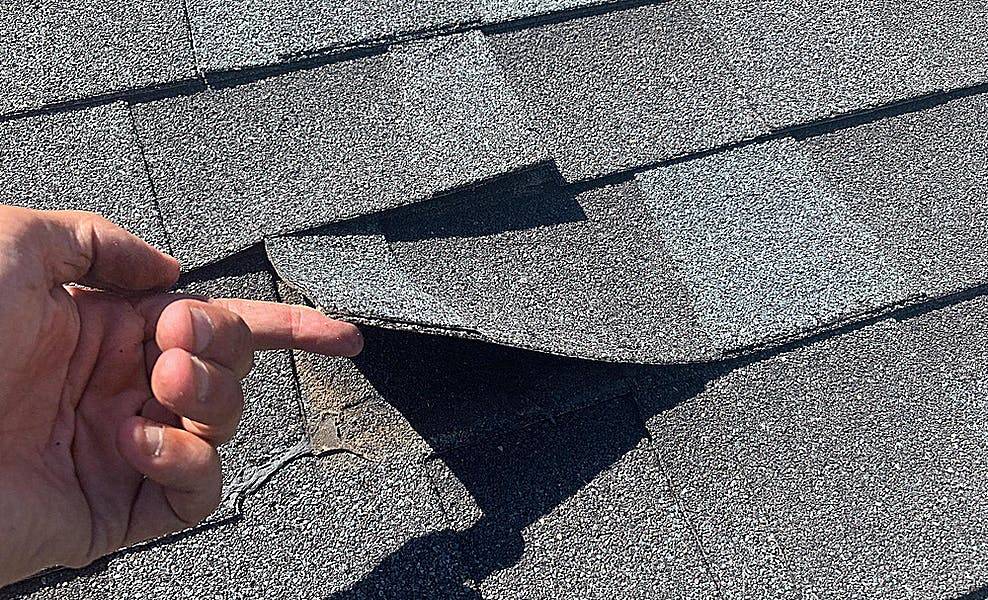 roofing expert lifting a single roofing shingle