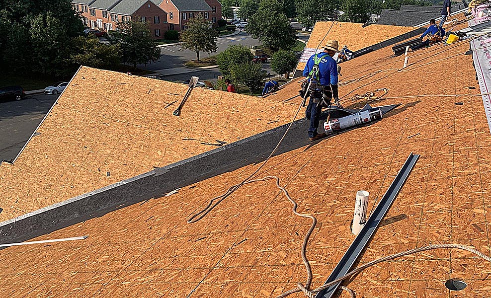 roofer replacing shingles on multipeaked apartment complex