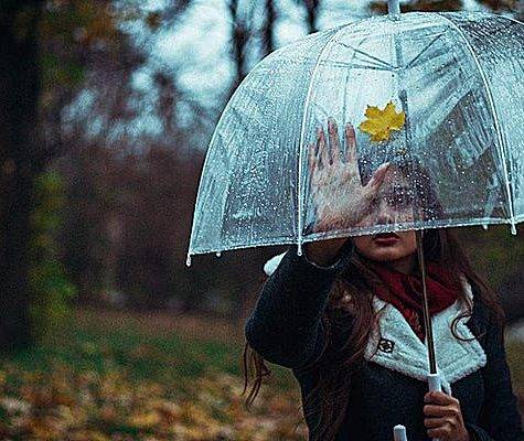 woman with umbrella looking back at house