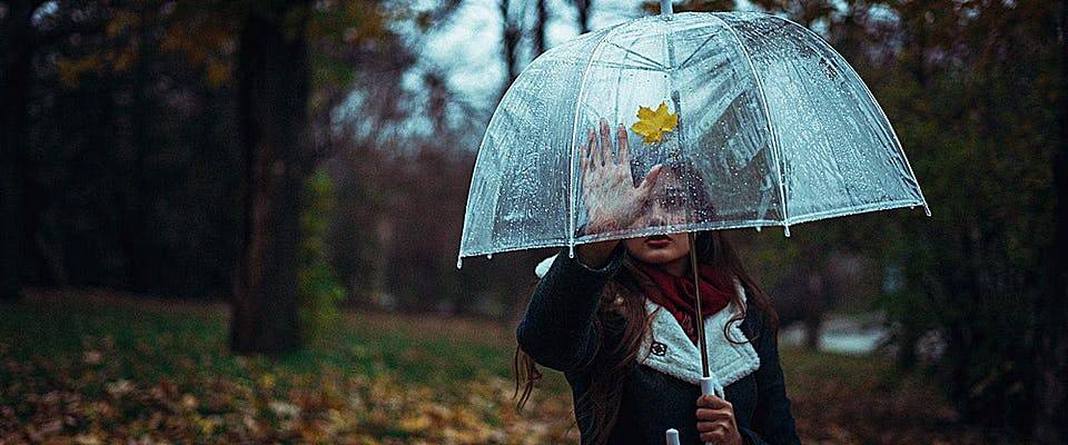 woman with umbrella looking back at house